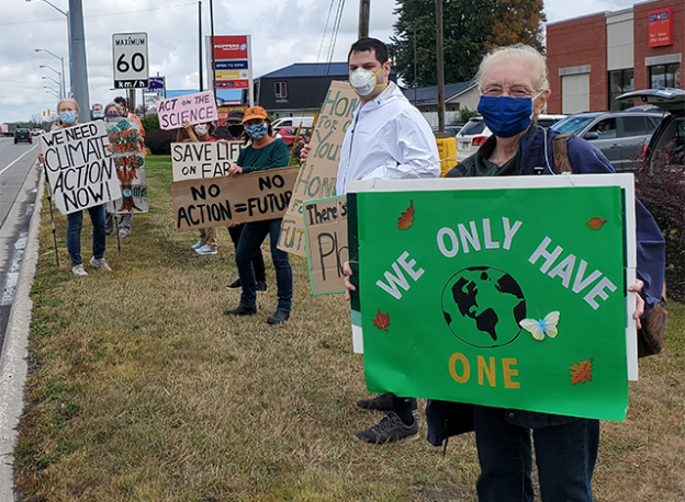 Seniors for Climate with signs say "WE ONLY HAVE ONE" with a picture of earth. Other signs that read, "WE NEED CLIMATE ACTION NOW!", "CLIMATE CHANGE KILLS", "HONK FOR CLIMATE ACTION" and more...